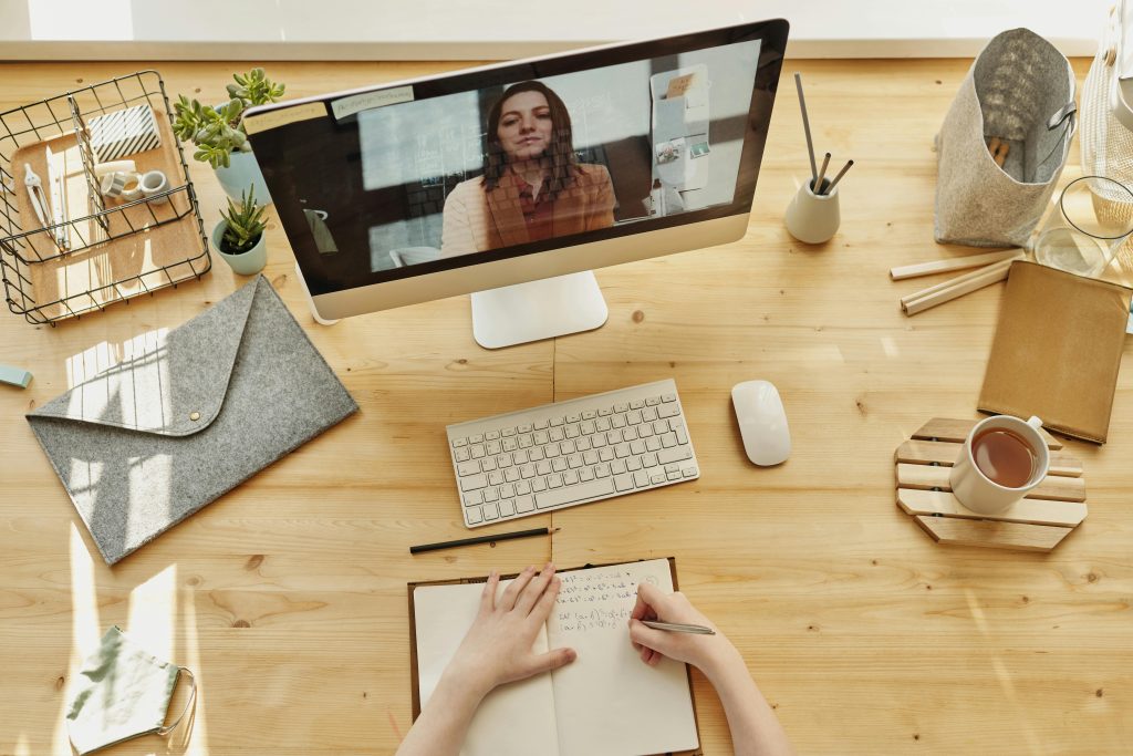 pexels-photo-4145190-4145190 Person taking notes during a video call at a neatly organized home desk, showing remote work lifestyle.